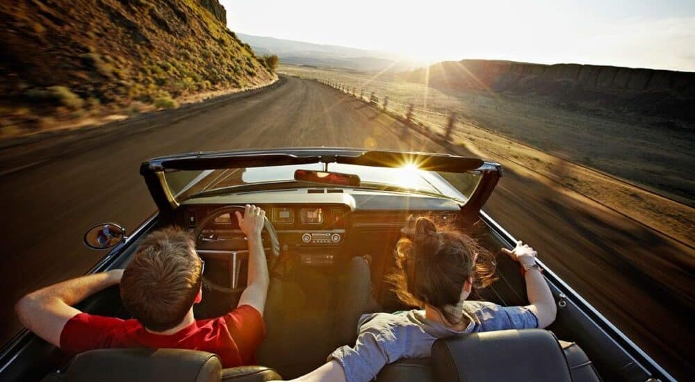 a couple in a car towards the sunset next to a mountain