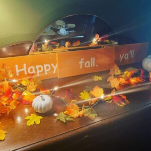 a wooden dresser with a white pumpkin and orange leaves on top